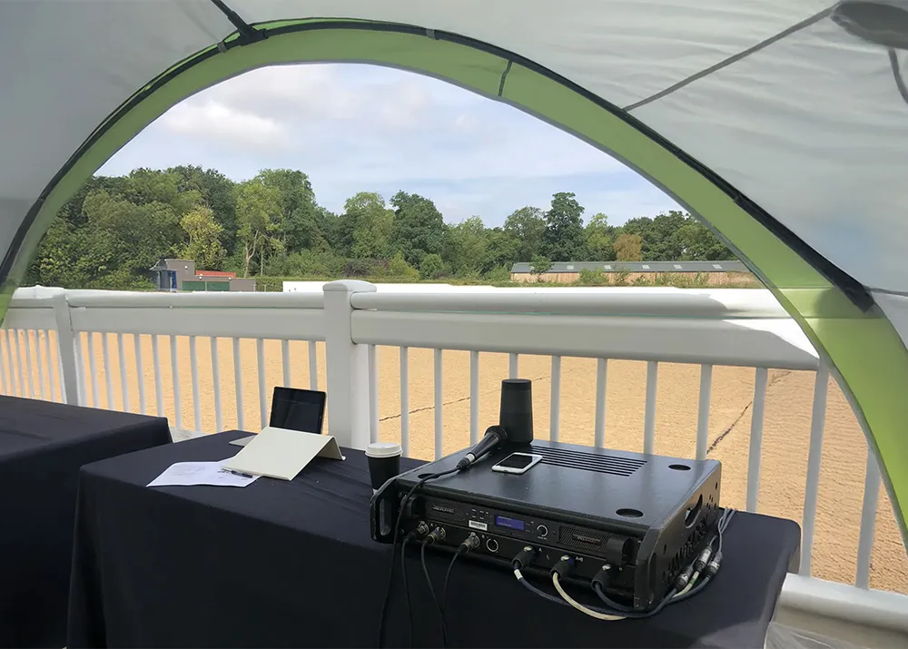 Event equipment setup under Coleman shelter with table, audio gear and microphone for outdoor use